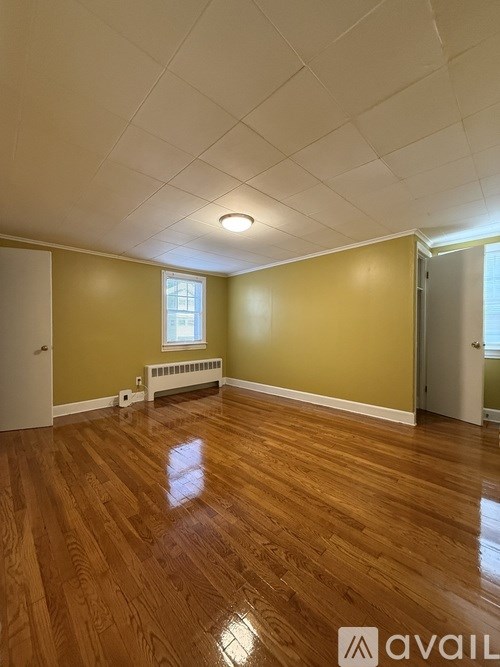 A room with wooden floors and a window with a radiator beneath it.