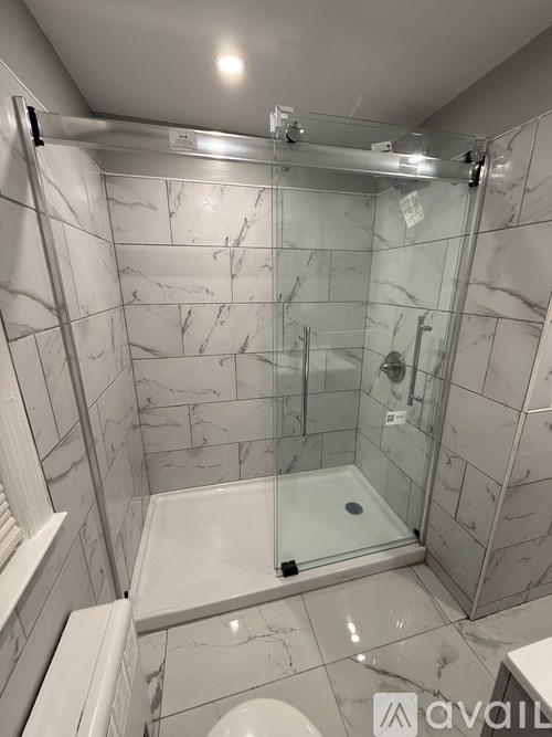 A bathroom with a marble tile shower and a glass door.