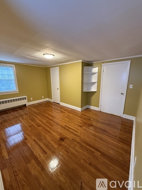 A room with wooden flooring and white walls.