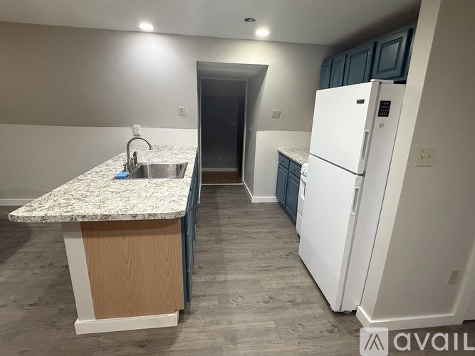 A kitchen with a granite countertop and a white refrigerator.