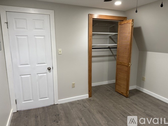 A room with a white door and a wooden closet with shelves.