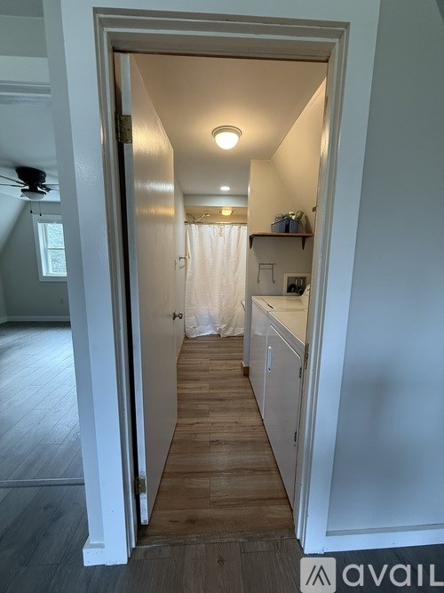A white doorway opens to a small kitchen.