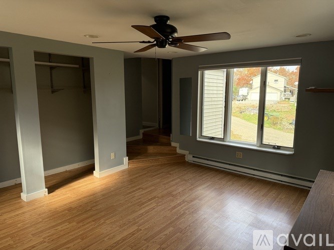 A room with a ceiling fan and wooden flooring.