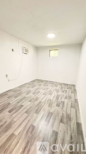 A room with wooden flooring and white walls.