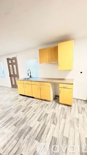 A kitchen with yellow cabinets and a grey floor.
