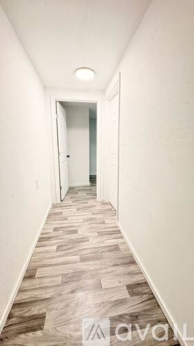 A hallway with wood flooring and white walls.