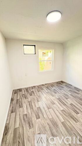 A room with a window and a wooden floor.
