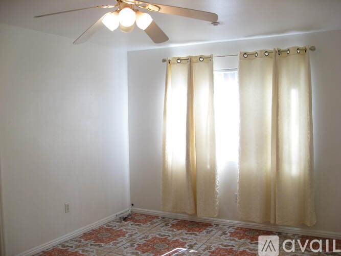 A room with a ceiling fan and curtains.