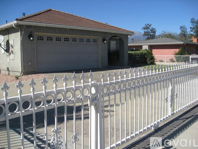 A white fence in front of a house with a garage.