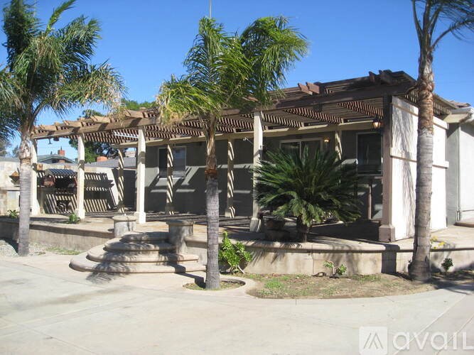 A house with a porch and palm trees in front.