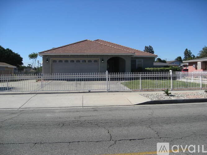 A house with a red roof and a white picket fence.