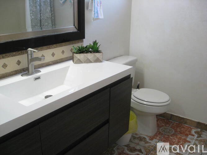 A bathroom with a white sink, toilet, and a mirror.