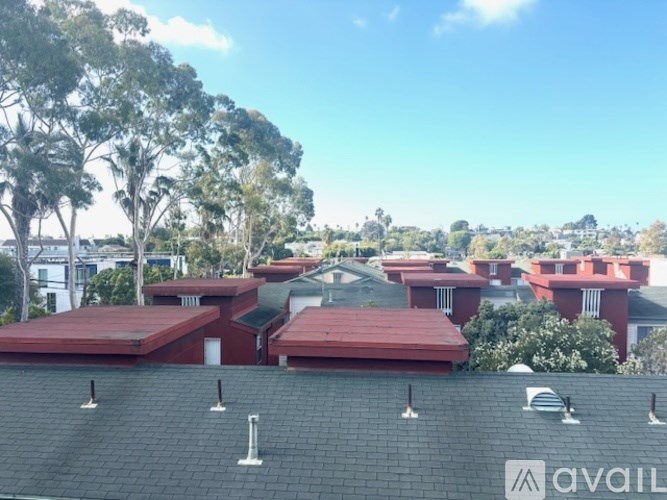 A view of a red roofed building with trees in the background.