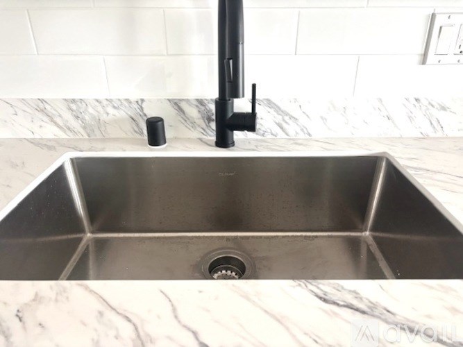 A modern kitchen sink with a black faucet.