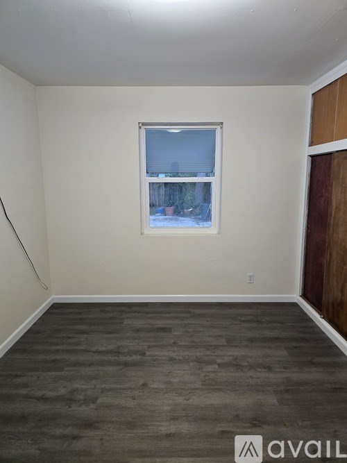 A room with a window and wooden flooring.