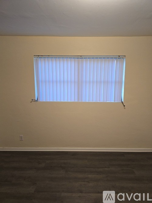 A room with a window covered by white blinds.