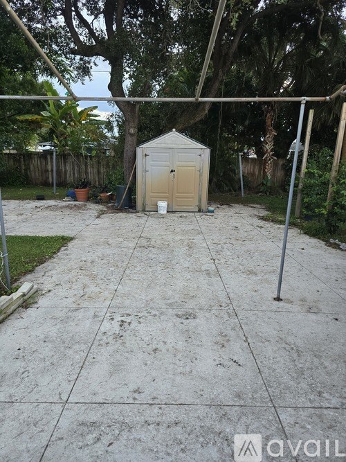 A concrete patio leads to a small shed in a backyard.
