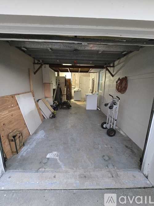 A large empty garage with a white refrigerator and a red fire hose on the wall.