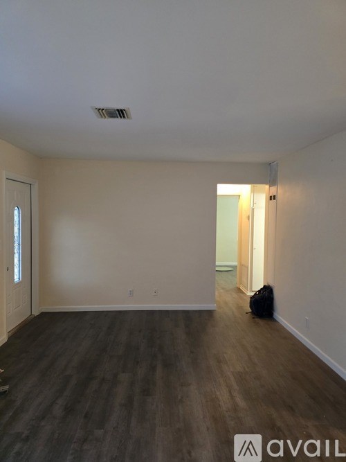 A room with wooden flooring and a wall-mounted air vent.
