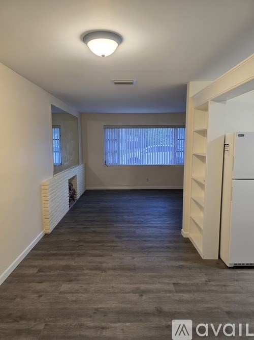 A room with a white refrigerator and a window with blinds.