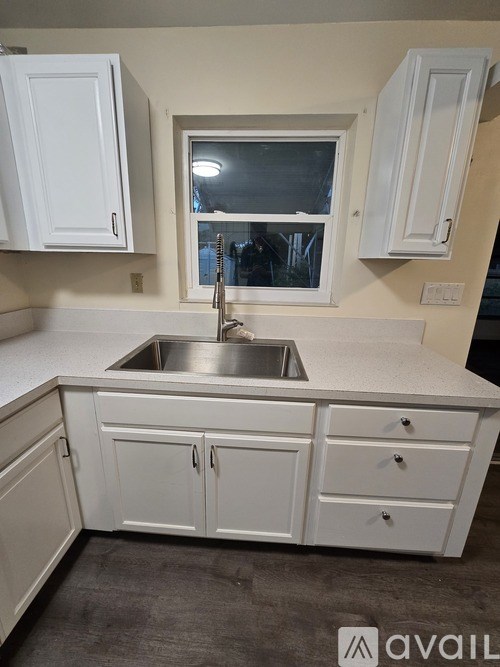 A kitchen with white cabinets and a stainless steel sink.
