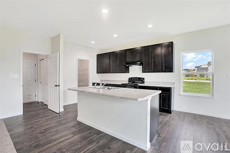 A modern kitchen with dark brown cabinets and a white island.