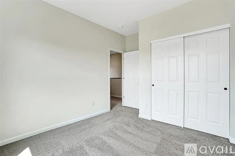 A room with a white door and a carpeted floor.