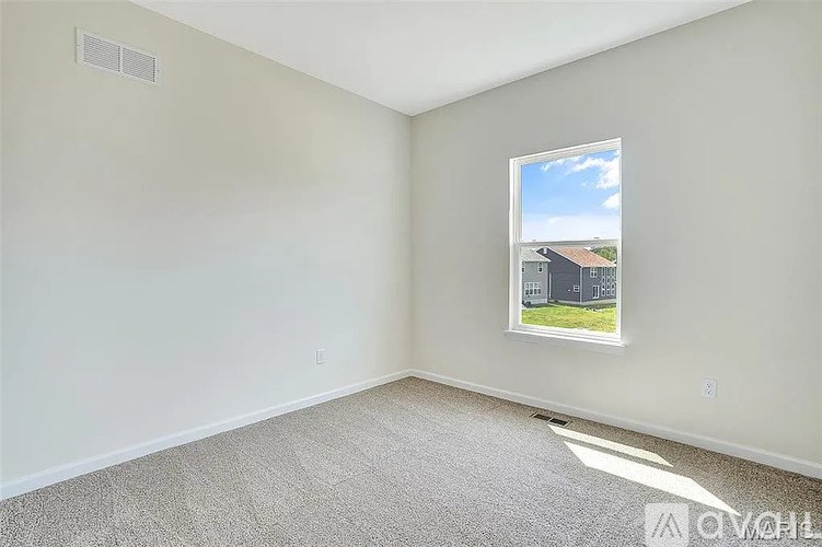 A room with a window showing a view of a house.