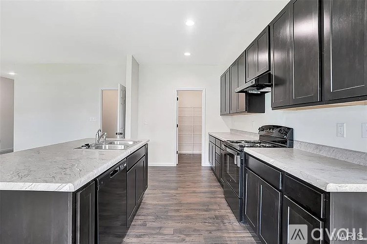 A kitchen with black cabinets and a marble countertop.
