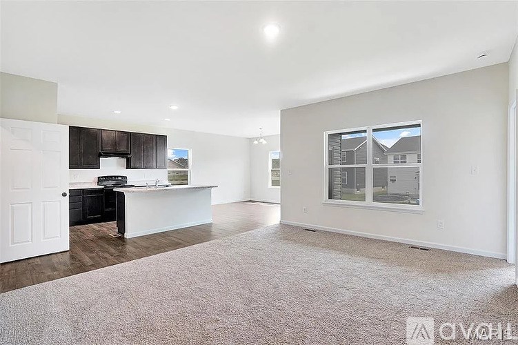 A spacious living room with a white carpet and a large window.
