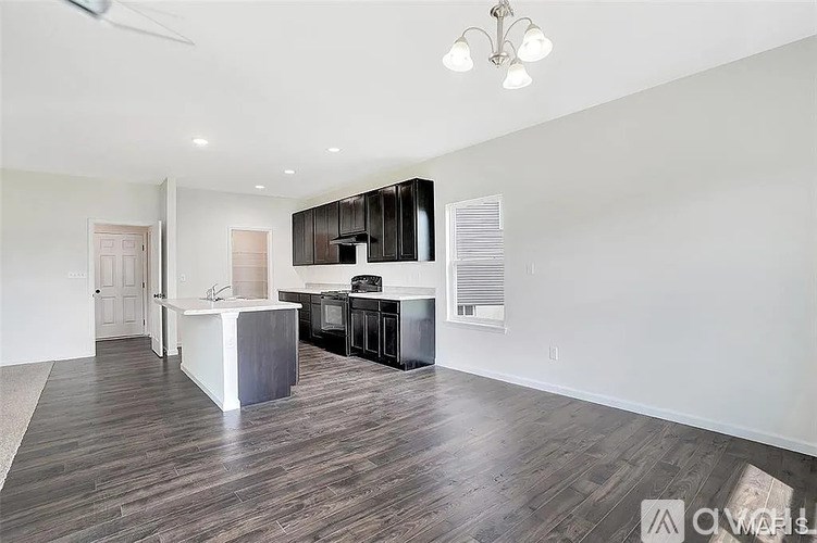 A modern kitchen with dark wood floors and white walls.