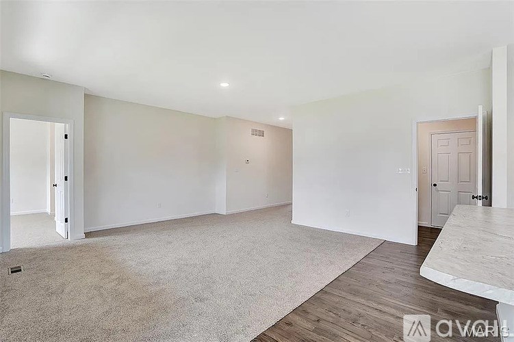 A spacious room with a carpeted floor and a white door on the left.