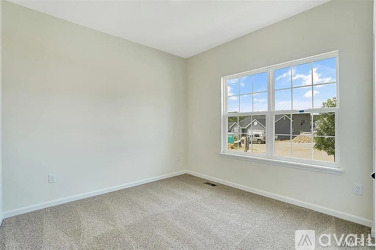 A room with a large window showing a view of a house and trees.