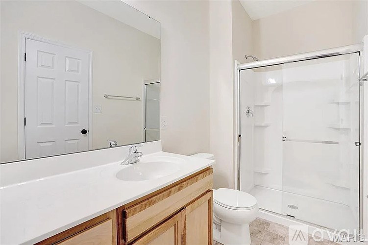 A white bathroom with a toilet, sink, and shower.