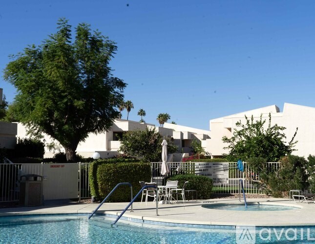 A pool with a ladder and a tree in the background.