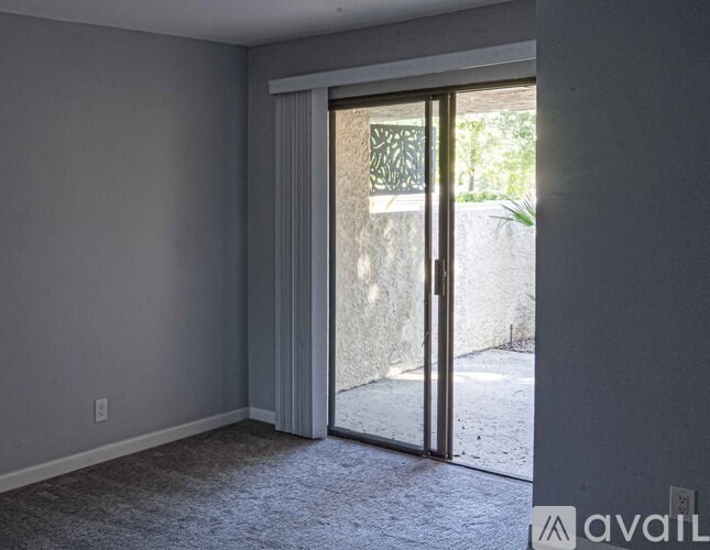 A room with a carpeted floor and a sliding glass door leading outside.