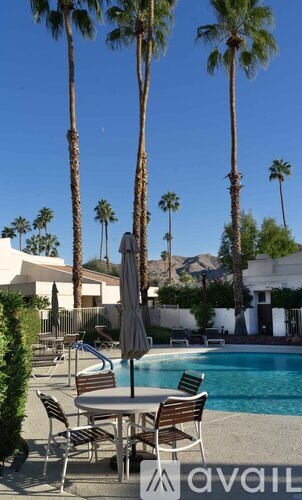 A pool surrounded by palm trees and chairs.