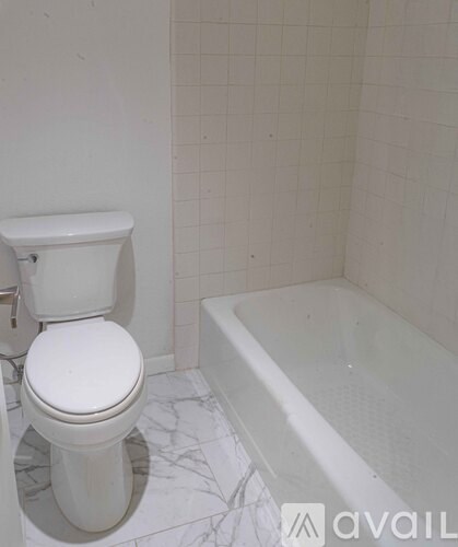 A white toilet sits next to a white bathtub in a bathroom.
