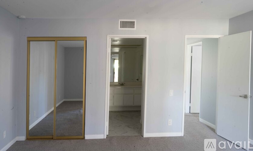 A room with a white wall and a mirrored door.