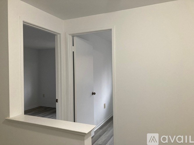 A white door with a black handle is in a white room.