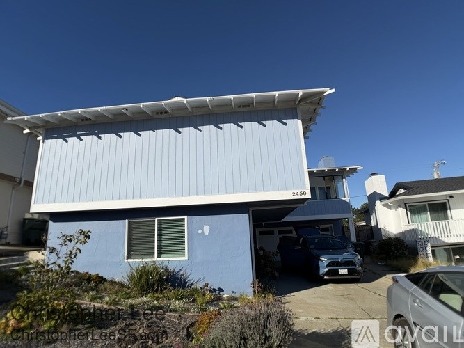 A blue house with a white garage door and a car parked in front.