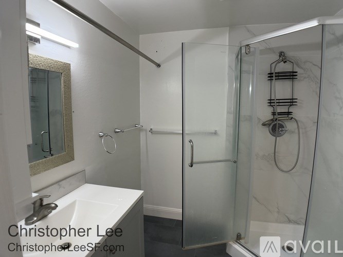 A bathroom with a white sink and a glass shower stall.