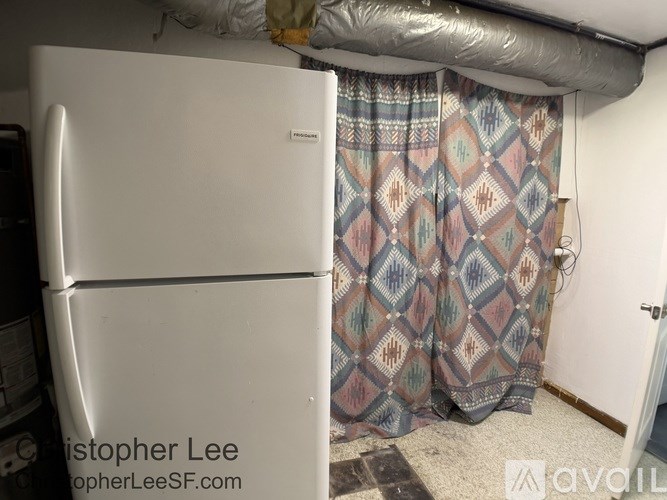 A white refrigerator with a patterned curtain hanging in front of it.