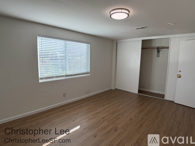 A room with wooden flooring and a window with blinds.