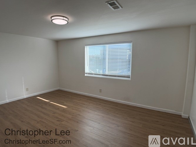 A room with wooden flooring and a window with blinds.