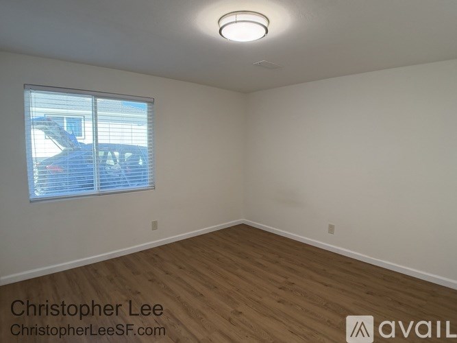 A room with wooden flooring and a window with blinds.