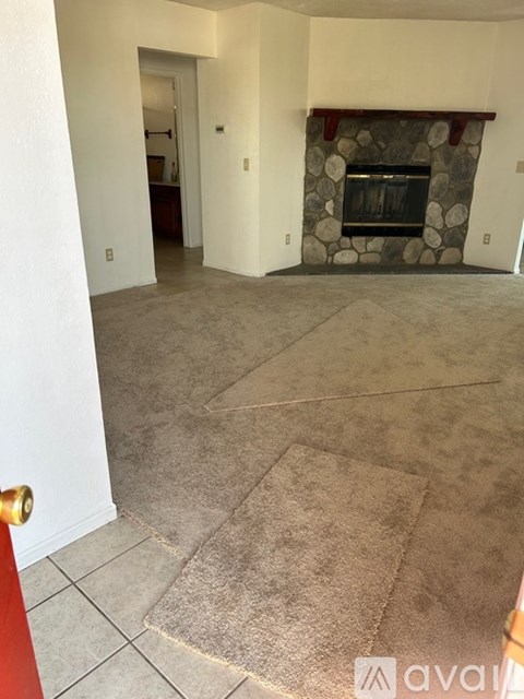 A living room with a fireplace and a carpeted floor.