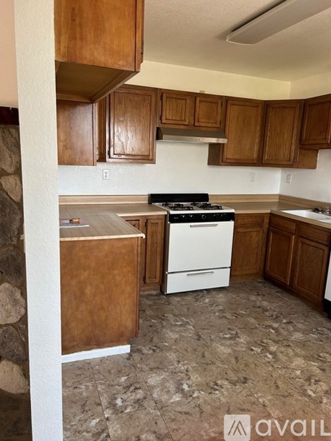 A kitchen with a white stove top oven and wooden cabinets.
