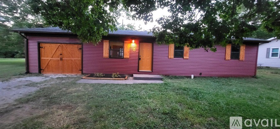 A red house with a brown garage door is available for rent.