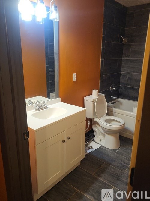 A bathroom with a toilet, sink, and cabinet.